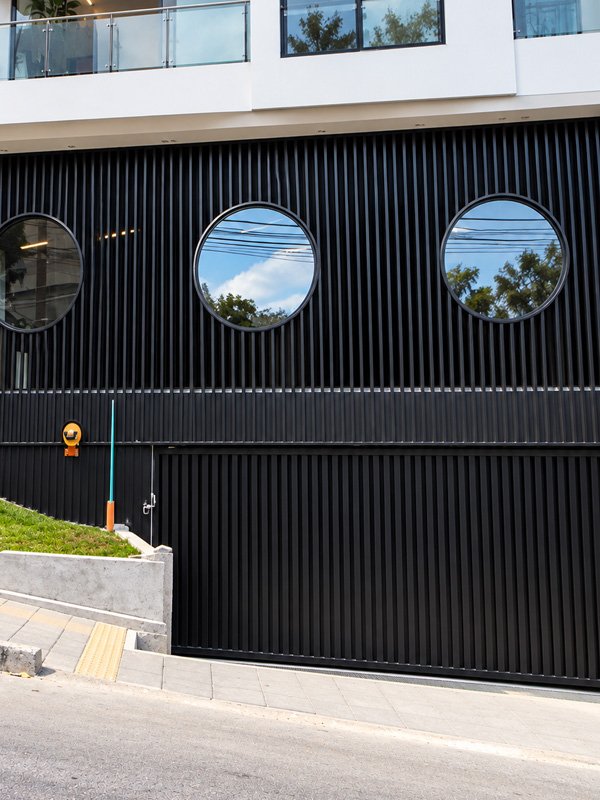 Puerta de garaje en aluminio negro con ventanas circulares