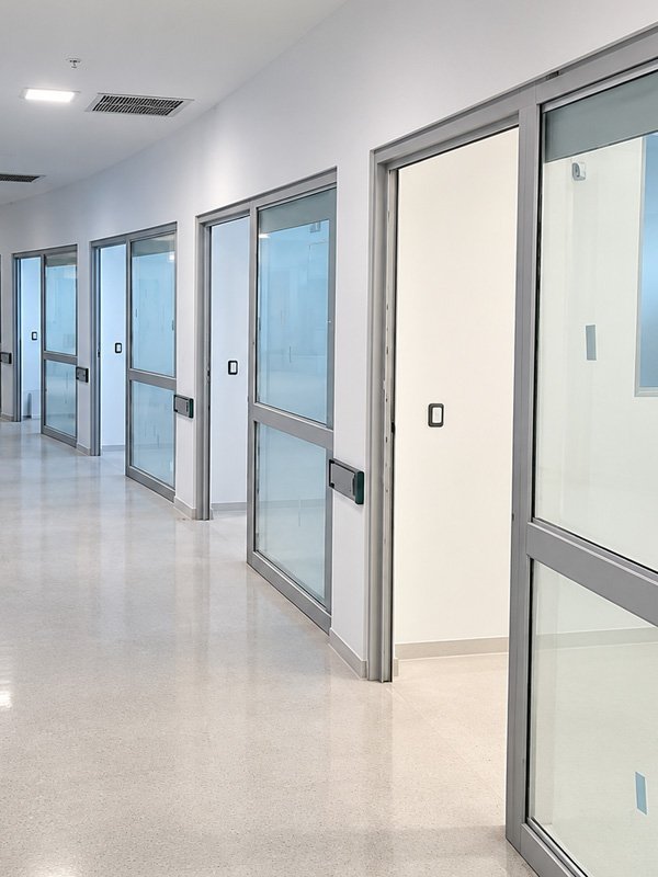 Puertas corredizas de aluminio y vidrio en un pasillo clínico